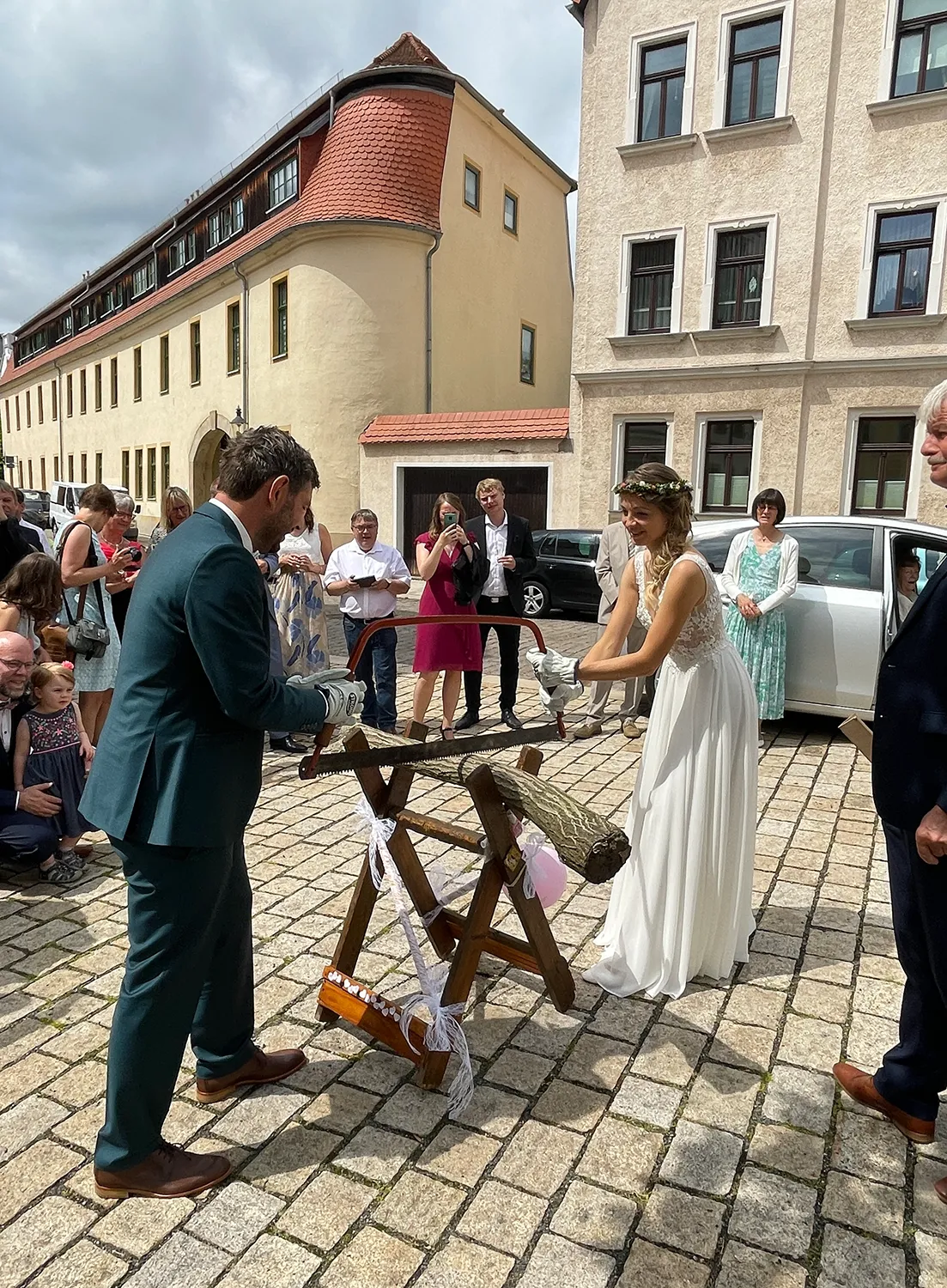 Traditionelles Baumstammsägen nach der Trauung – Hochzeit mit Gästen und musikalischer Begleitung von DJ Dobbi