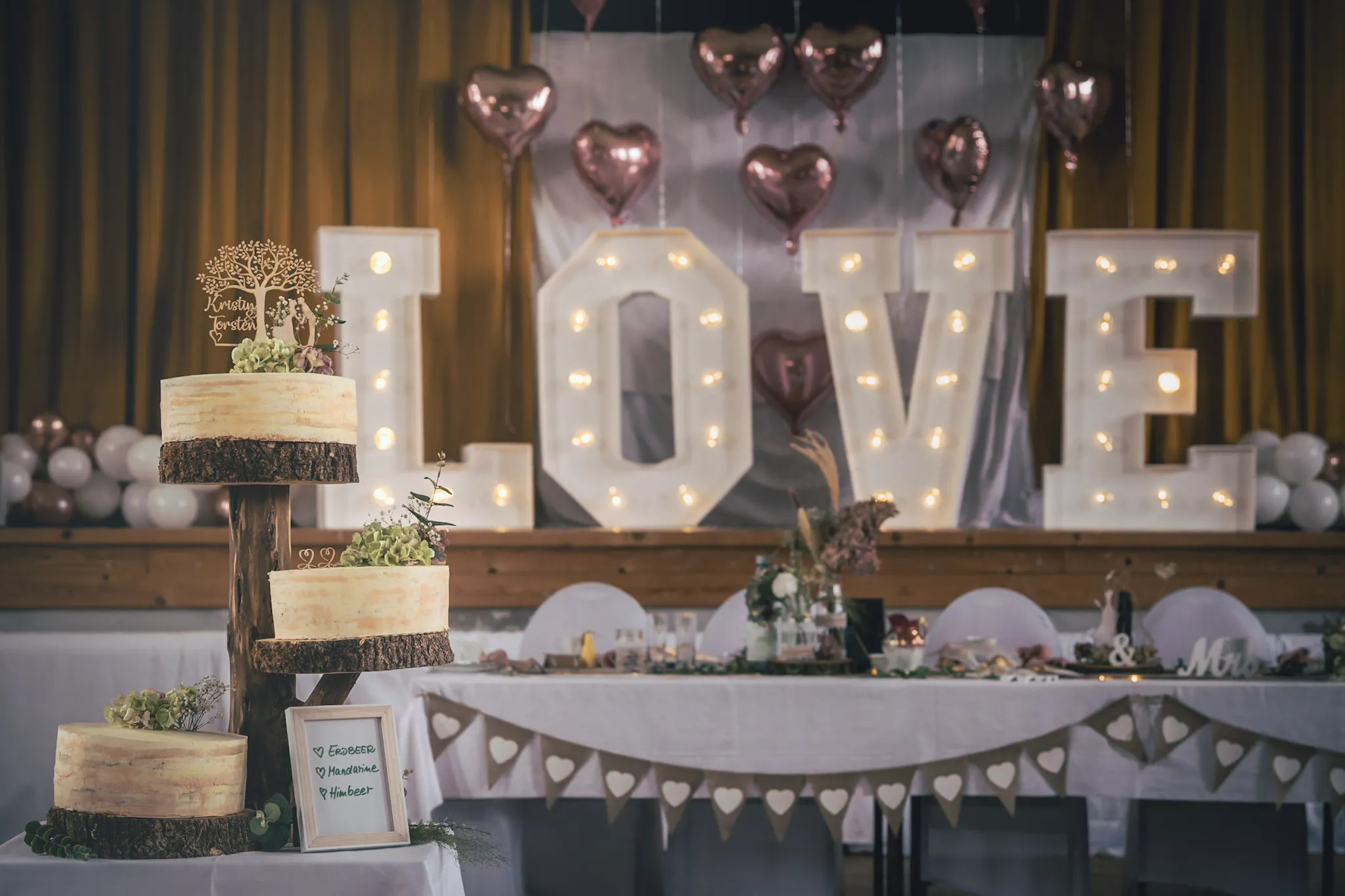Hochzeitstorte und festlich geschmückte Location mit LOVE-Leuchtschrift – romantische Feier mit DJ Dobbi